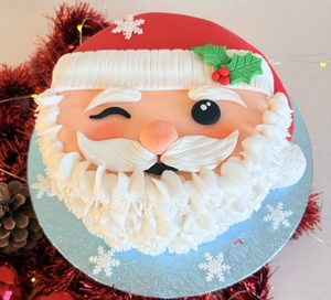 Jolly Santa Christmas cake with winking Santa face, fondant beard and holly detail