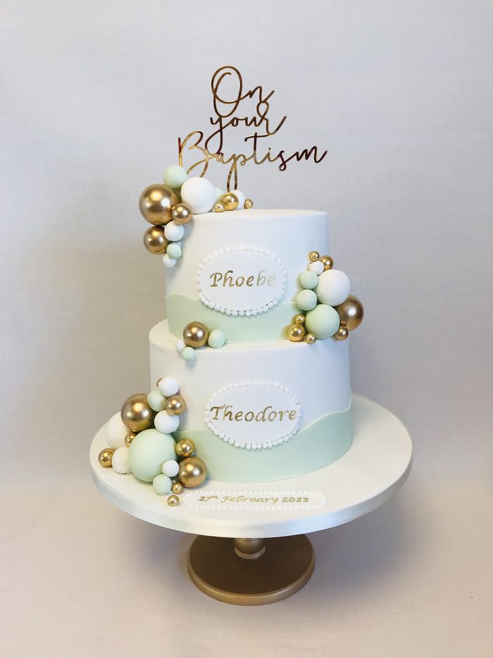 Two tier christening cake with gold and green sugar balls and an On your Baptism topper