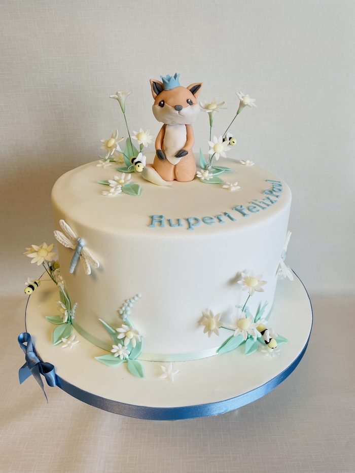 Christening cake with a sugar fox, daisies and bees on a clean white iced finish